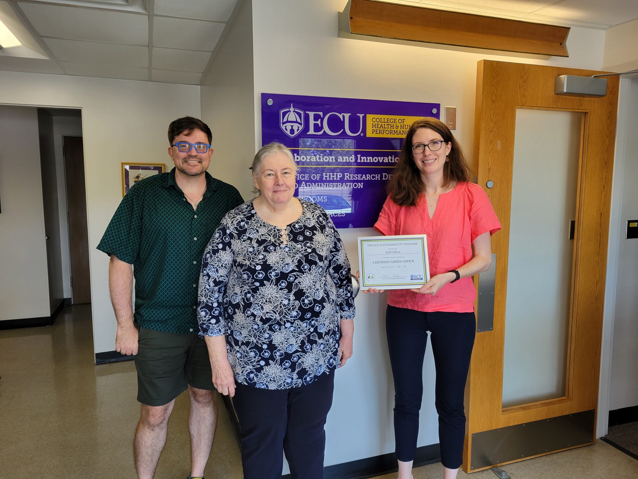 Three members of the ADR office atand smiling and holding a Green Office Certificate