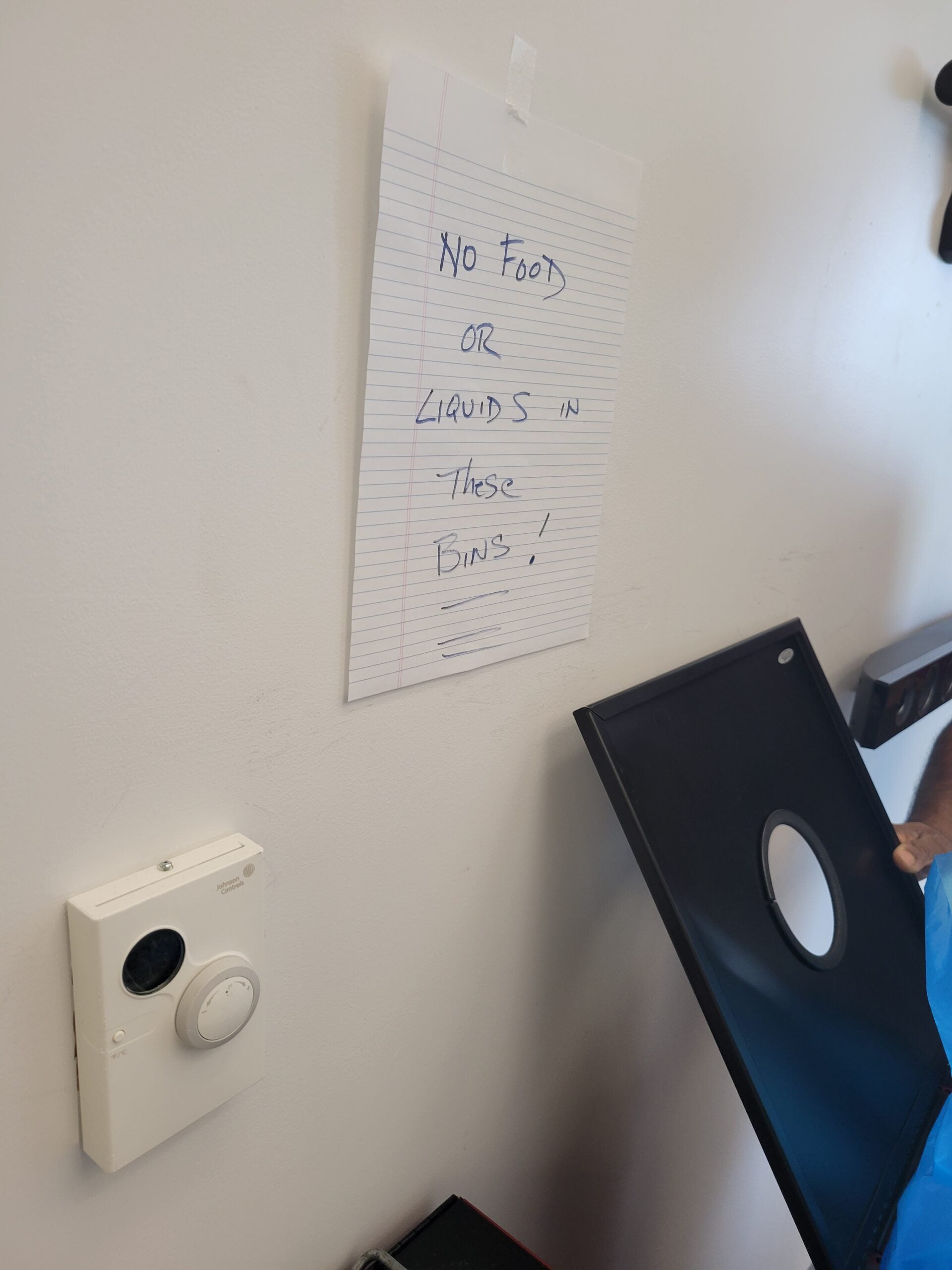 A handwritten sign saying "No food or liquids in these bins!" posted next to the recycling bins