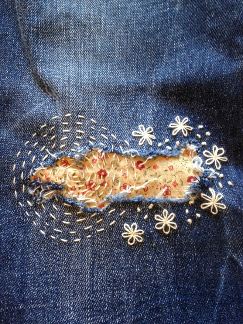 a yellow patch on a hole in jeans with yellow flowers embroidered around the edges