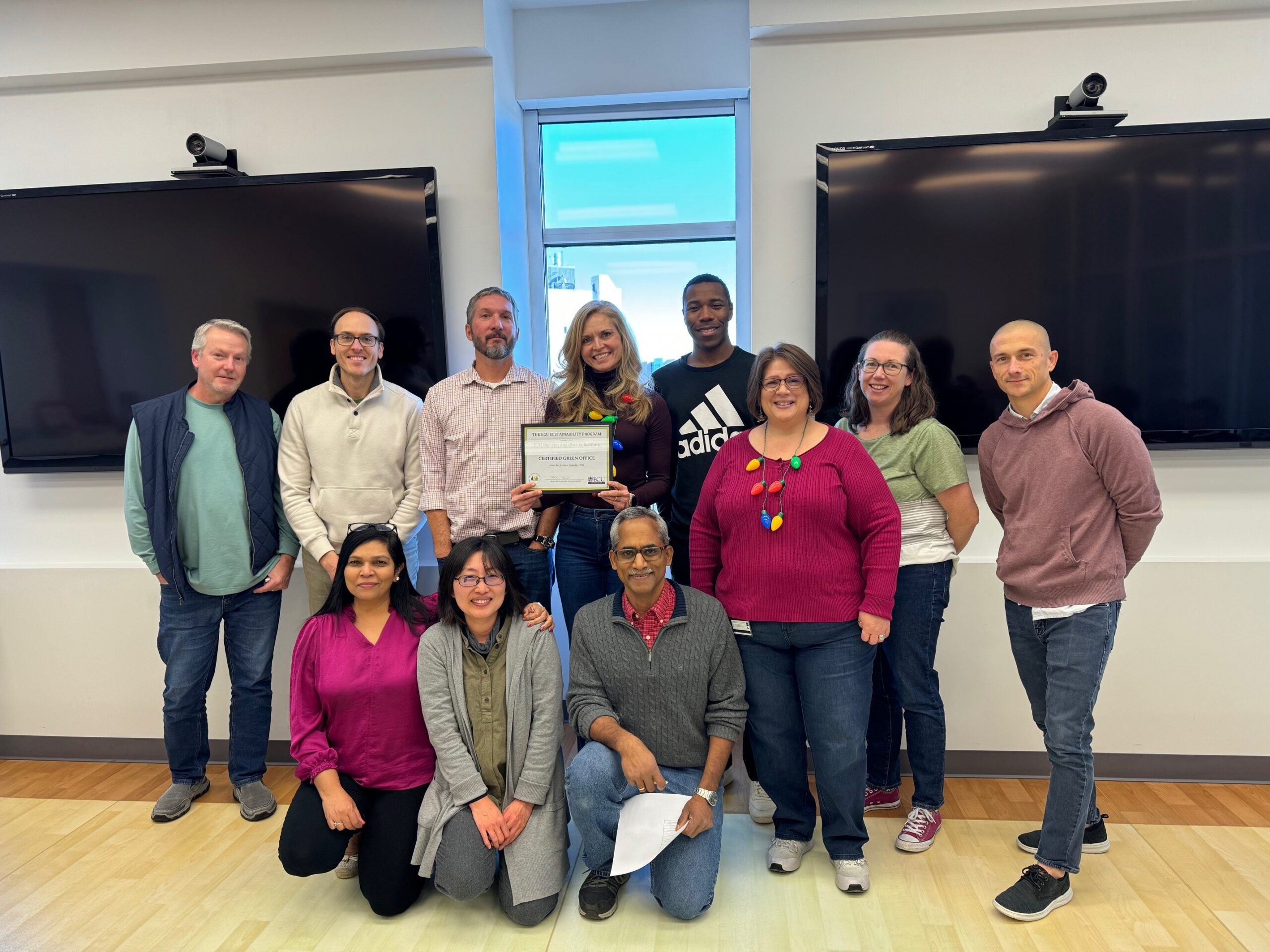 A group of employees from ECU's Diabetes and Obesity Institute stand in a group with a framed Green Office certificate