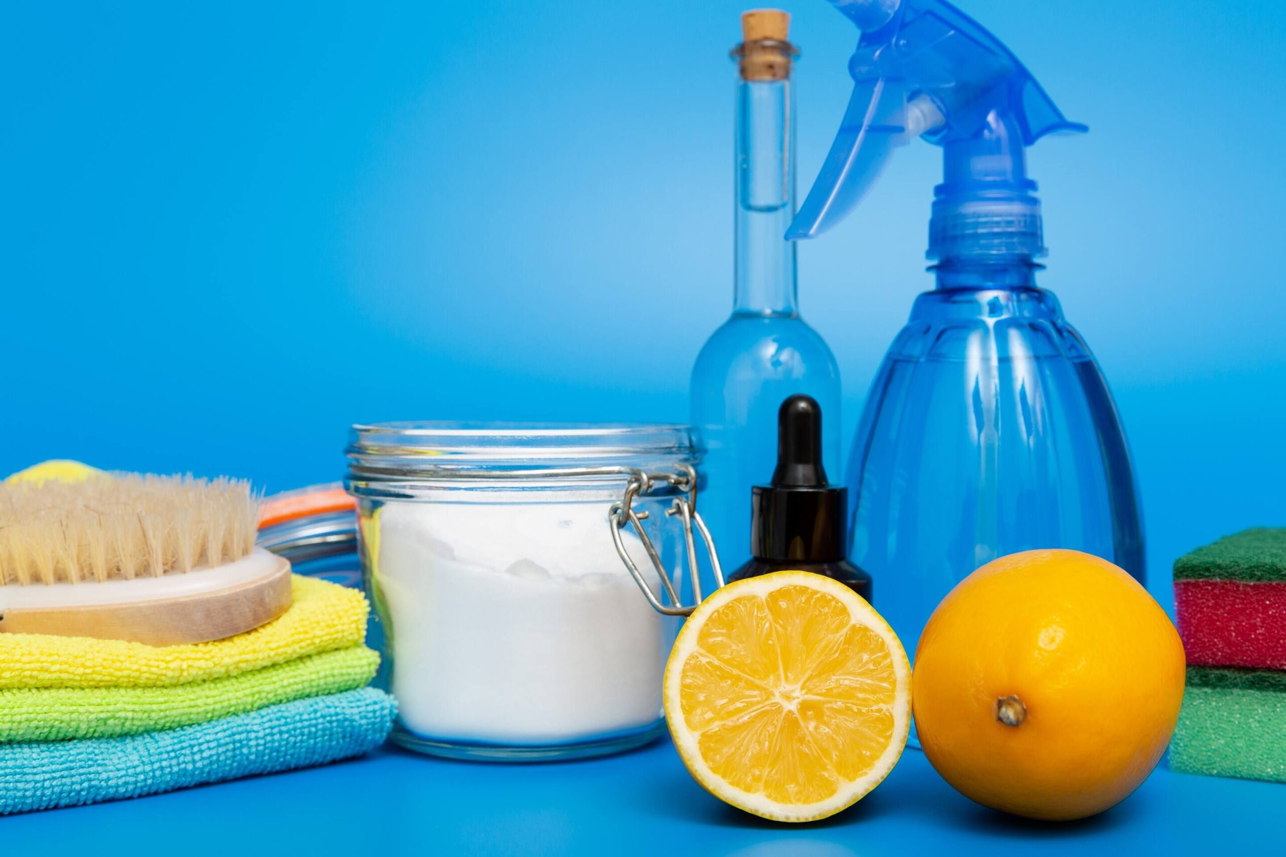 Reusable spray bottles and cloths as well as baking soda and oranges (used to make sustainable cleaning supplies)