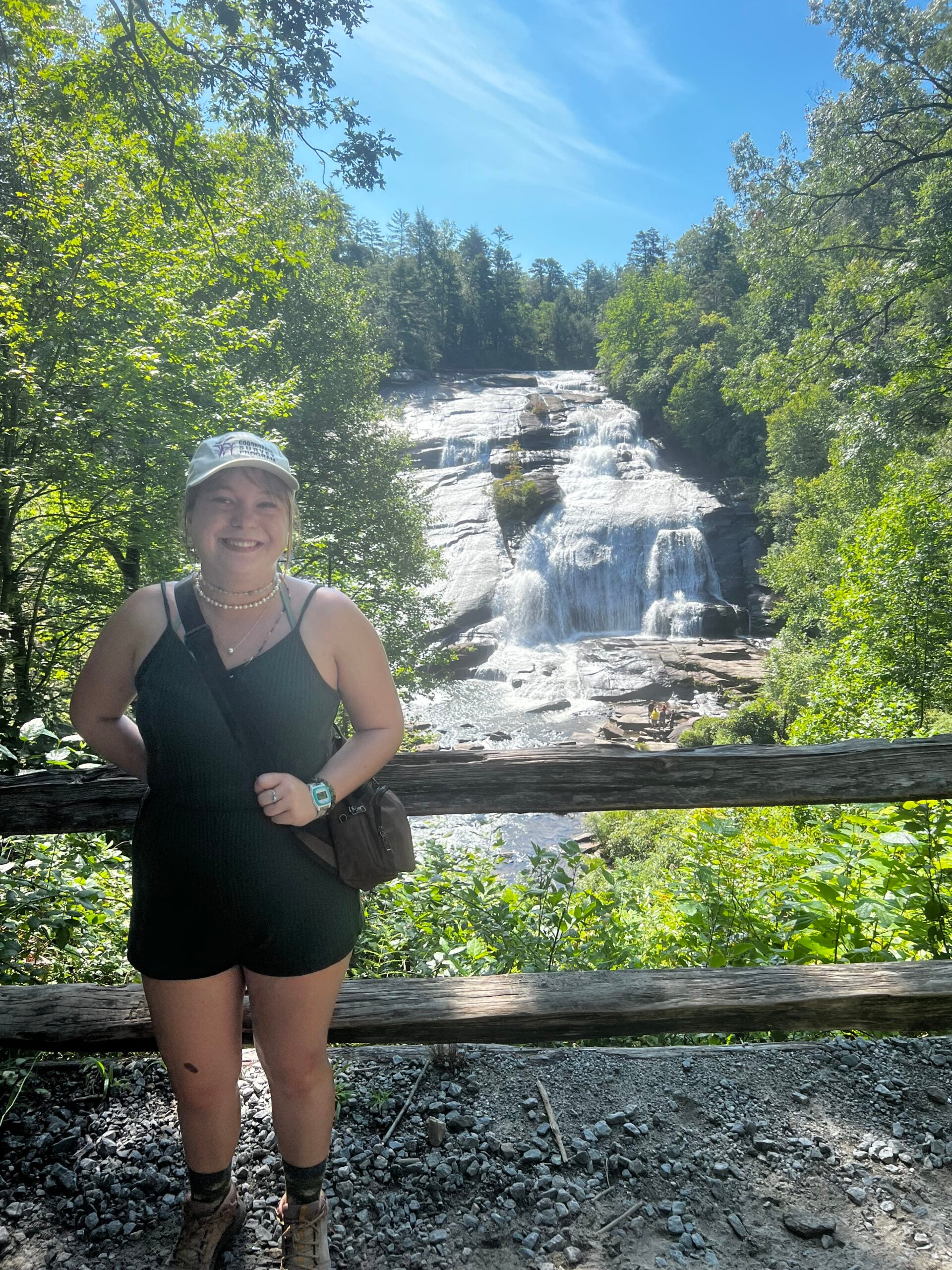 Young woman smiles with a waterfall in the background.