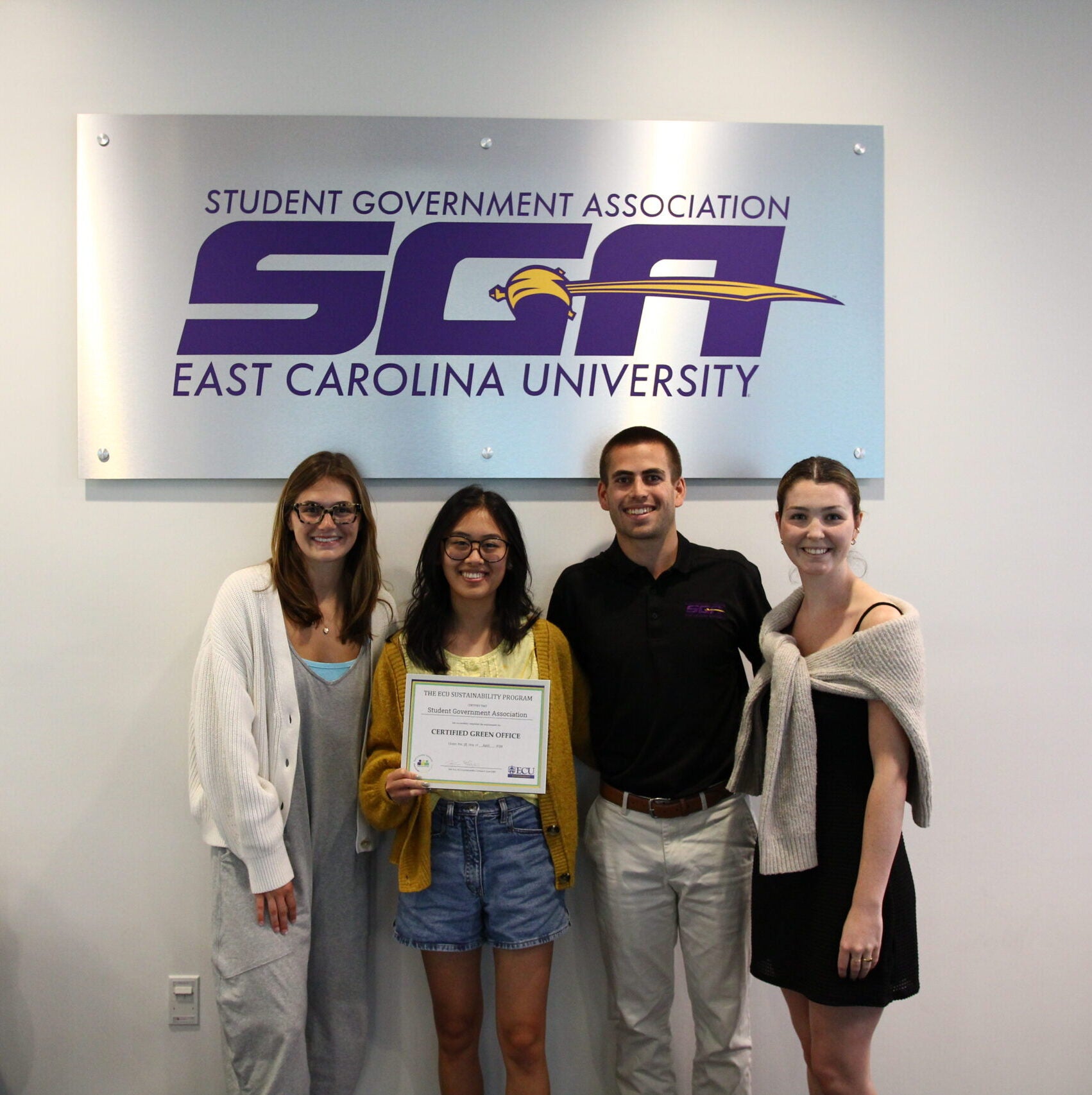 A photo of four members of SGA holding a Green Office Certificate and smiling.