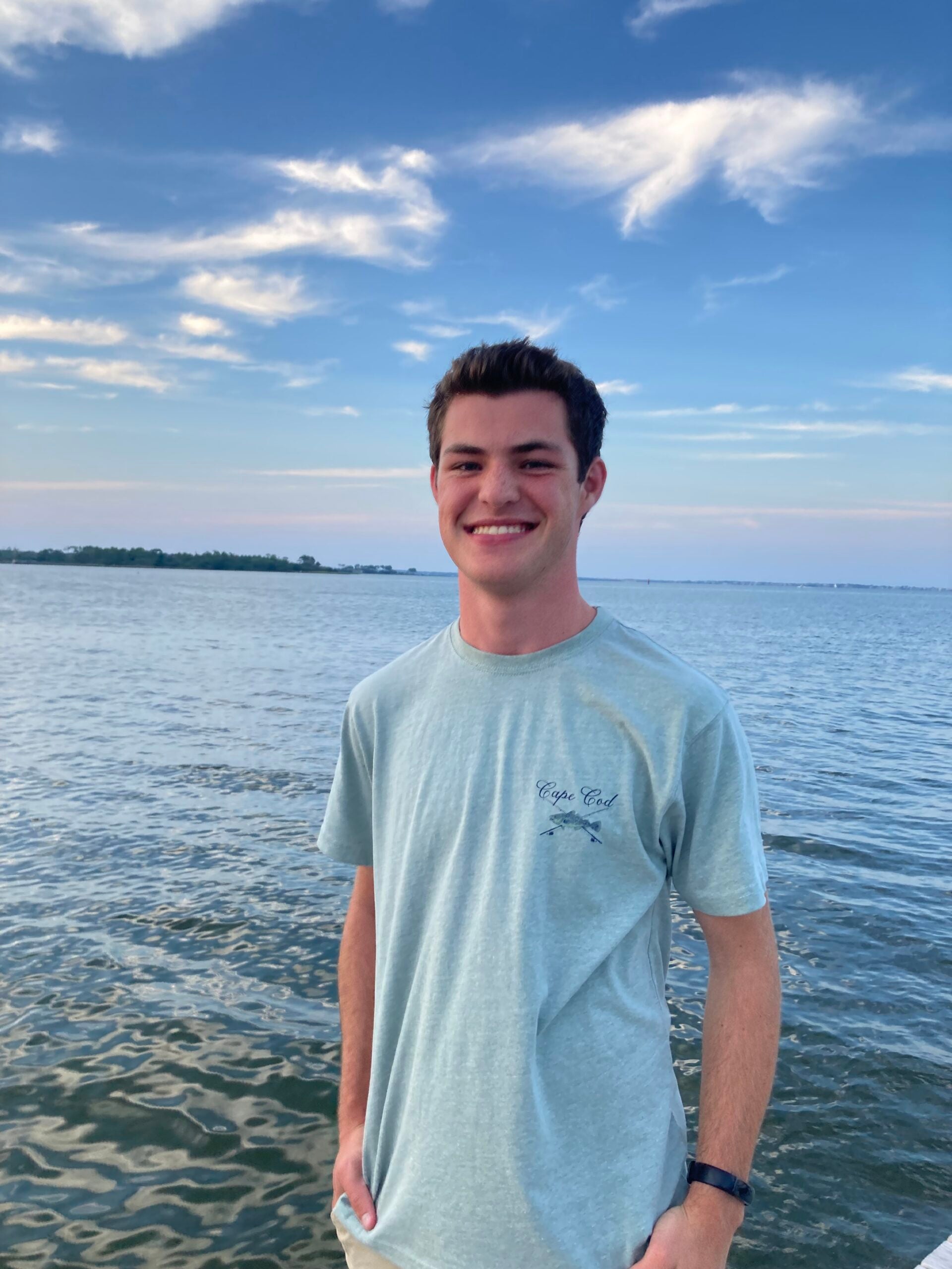 Young man stands in front of ocean.