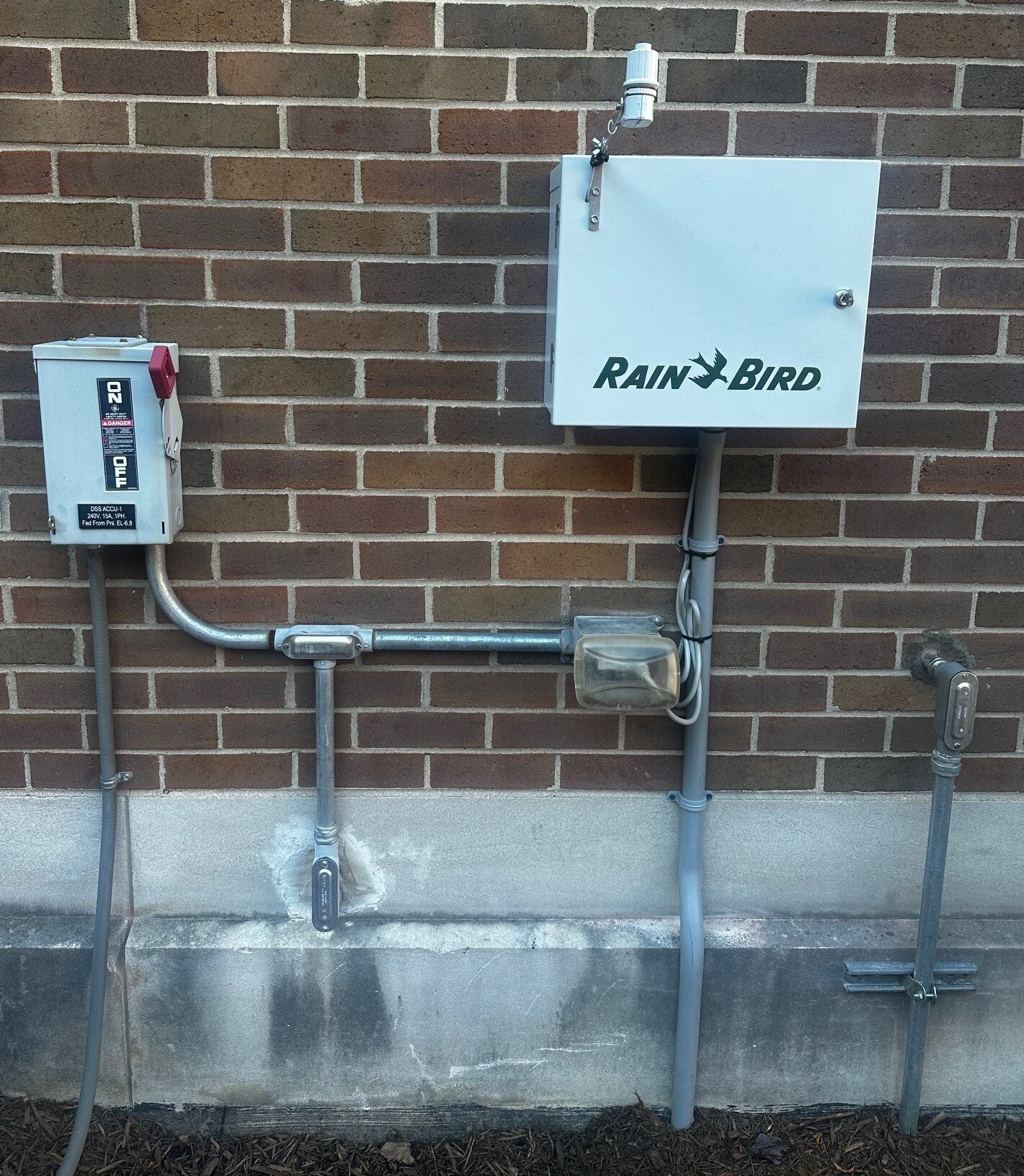 a "rain bird" irrigation system on a brick wall in the courtyard