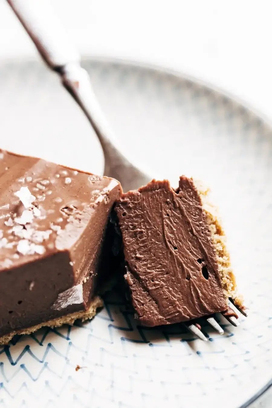 A chocolate pie slice on a plate with a bite on a fork next to it