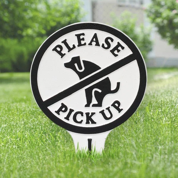 A sign in a grassy field asking dog owners to please pick up after their pets