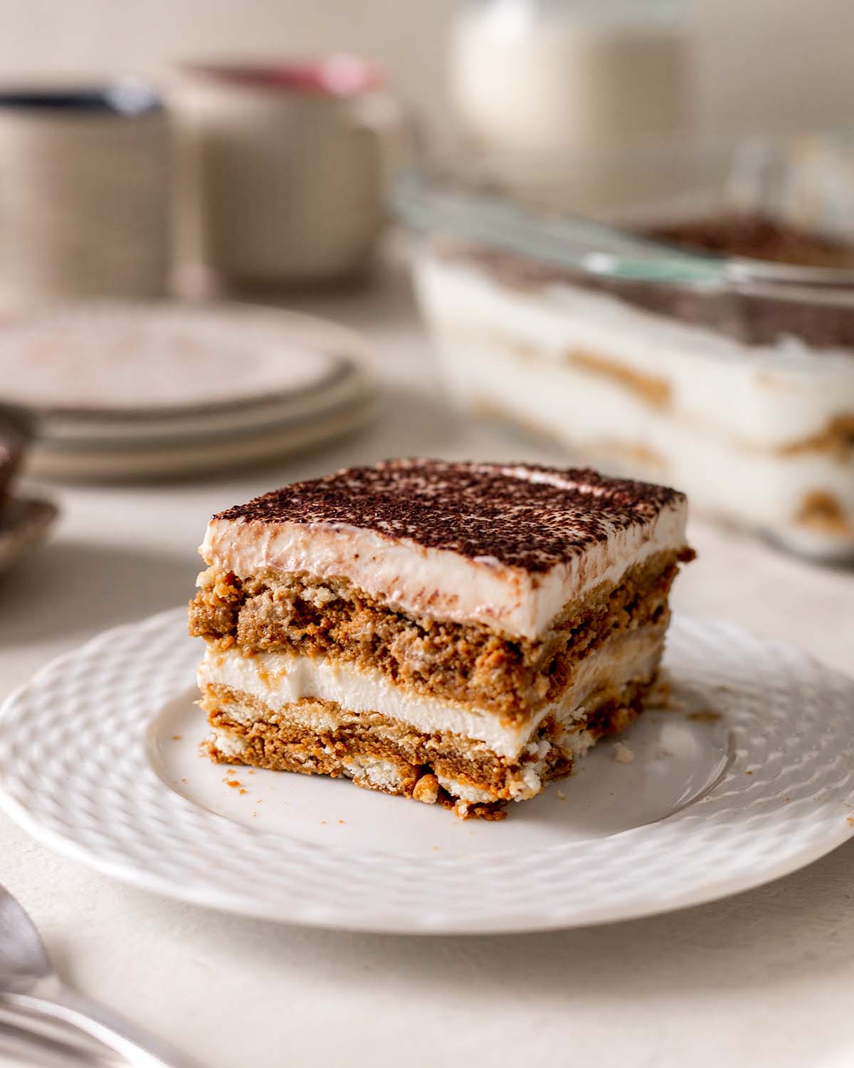 A piece of tiramisu on a plate shown from the side