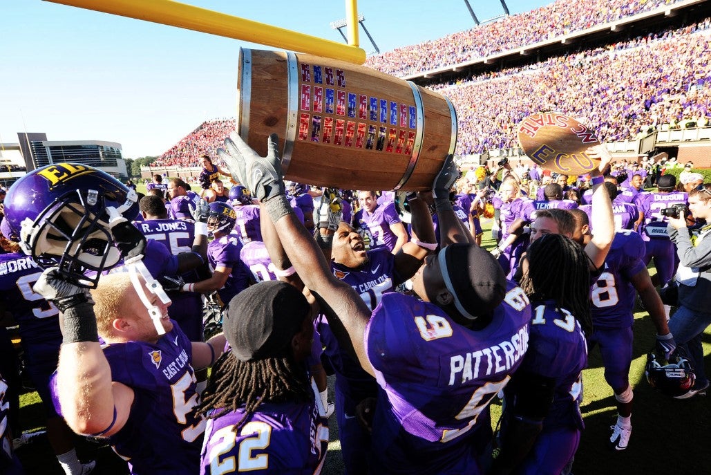 a crowd with ECU football players in their purple uniforms