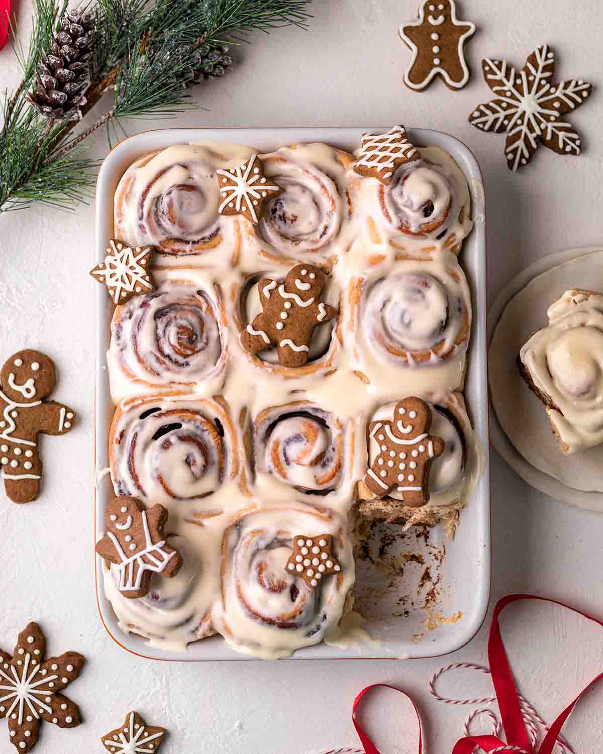 a photo of cinnamon rolls with icing pictured from a bove with small gingerbread men decorating the pan